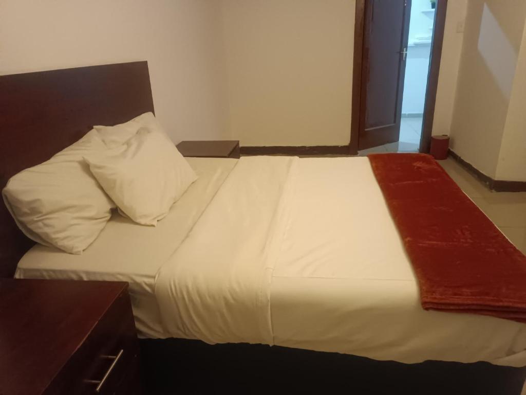a large white bed with a red blanket on it at Khaya Mnandi Leisure Suites in Pretoria