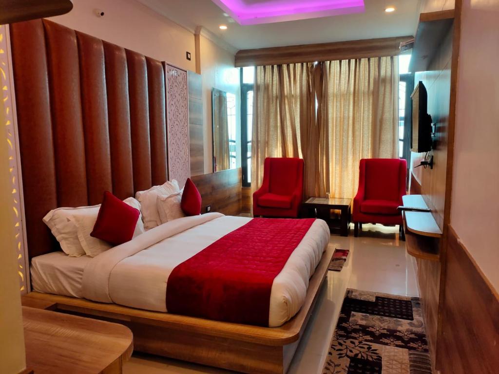 a bedroom with a bed and two red chairs at Grand Hill mall road Mcleodganj in Dharmsala