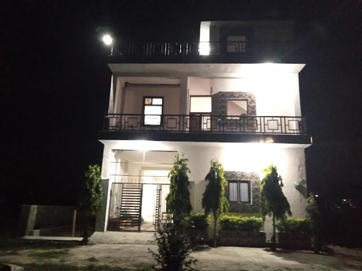 a large white house with a balcony at night at Atithi home stay in Rāmnagar