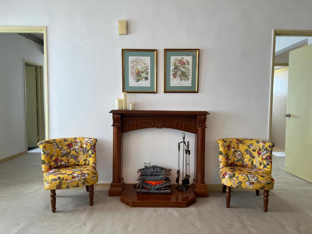 2 sillas en una sala de estar con chimenea en Cloud Forest Homestay Genting Highlands, en Genting Highlands