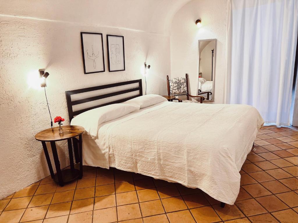 ein Schlafzimmer mit einem großen weißen Bett und einem Tisch in der Unterkunft Stecadó Casté - Nel centro storico del paese in Dolceacqua
