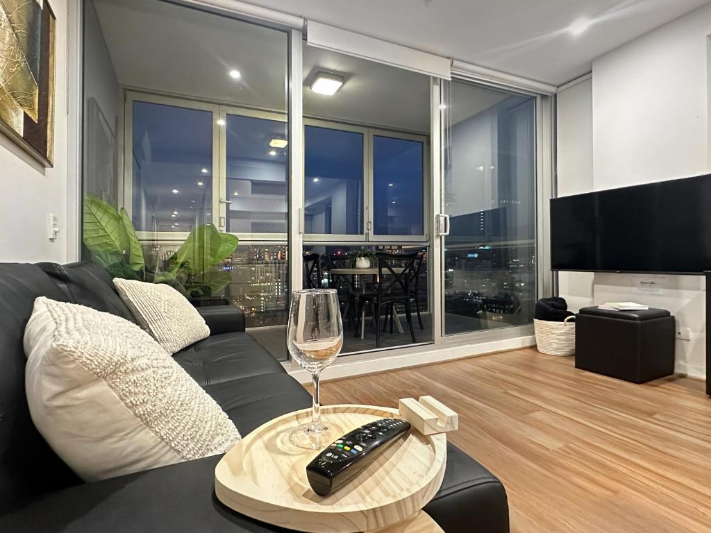 een woonkamer met een bank en een glas wijn bij CBD Penthouse View Apartment in Adelaide