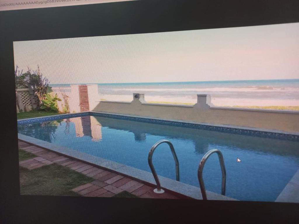 チェンナイにあるHappy Beach Houseのビーチを望むスイミングプールをテレビ画面で見ることができます。