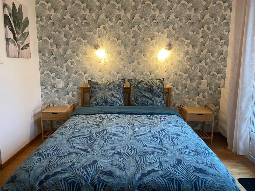 a bedroom with a bed with a blue comforter at Chambre Sérénité avec SDB privée - 'Les 7 Sources' 