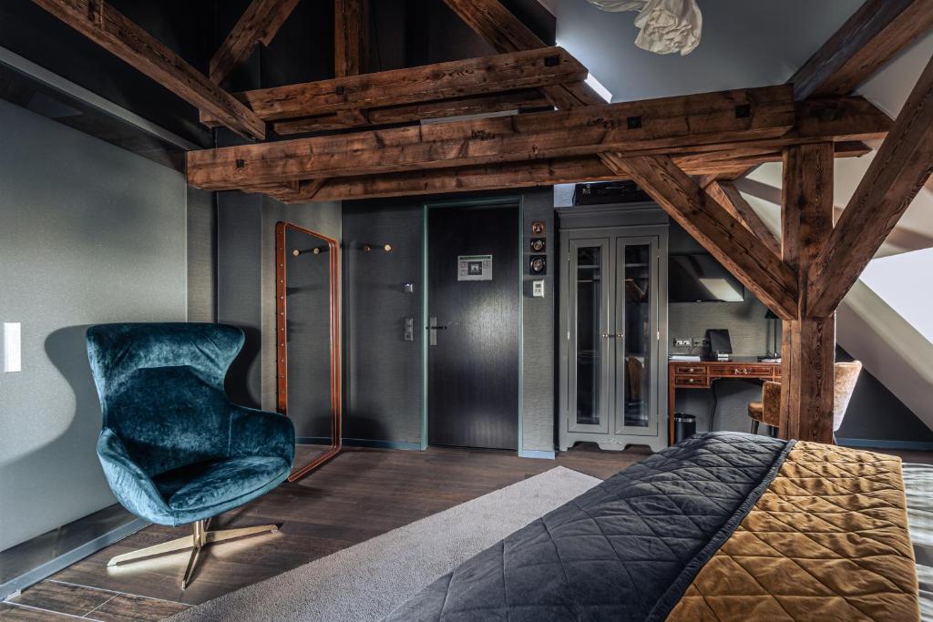 a bedroom with a blue chair and a desk at Boutique Hotel Spedition a member of DESIGN HOTELS in Thun