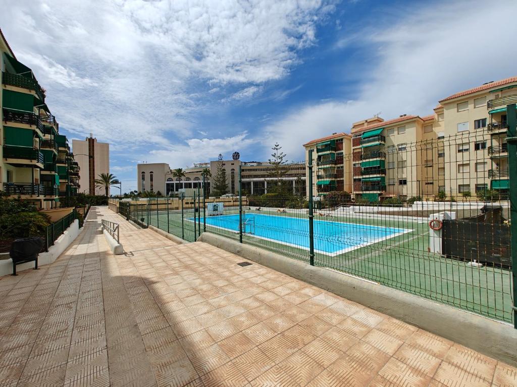 a fence around a swimming pool in a city at Sun Apartment Cristimar (3 bedrooms) in Los Cristianos