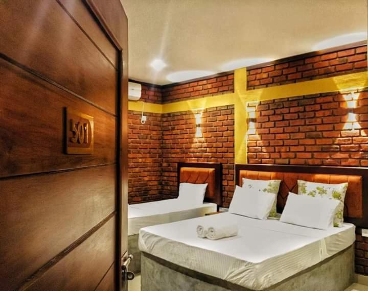 a bedroom with two beds in a brick wall at New saniro airport sports hotel in Gampaha