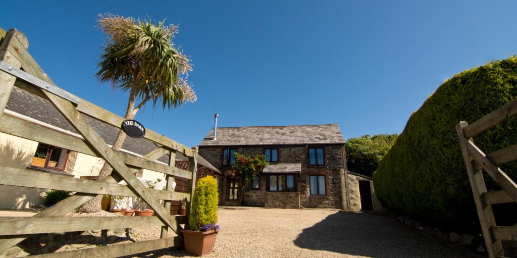 a house with a fence and a palm tree at Red Fox Barn in Perranporth