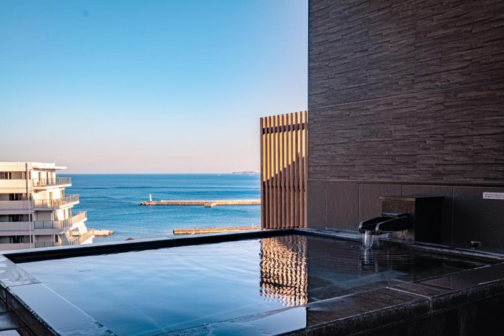 a swimming pool with a view of the ocean at Hotel Kan-ichi in Atami