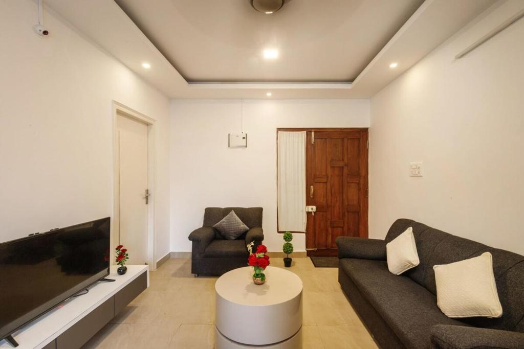 ein Wohnzimmer mit einem Sofa und einem TV in der Unterkunft Downtown Apartment by JadeCaps AC 2BHK Near CBD in Bangalore
