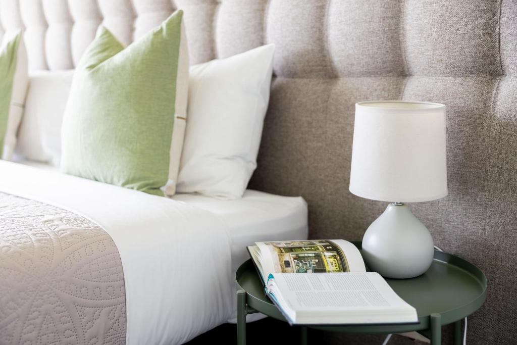 a bed with a table with a book and a lamp at The Apollo in Apollo Bay
