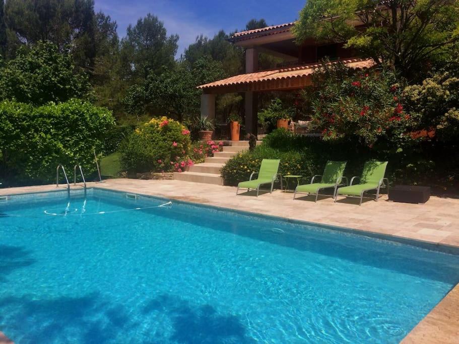 una piscina con sillas verdes y una casa en appartement T3 dans propriété de 5000m2 avec piscine, en Venelles