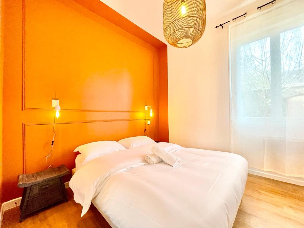 une chambre avec un lit blanc avec un mur orange dans l'établissement Le Maine, Proche Gare, à Saint-Nazaire