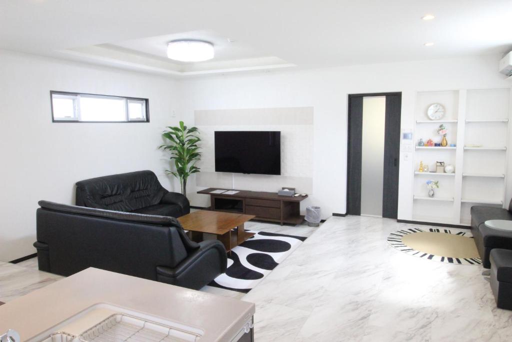 uma sala de estar com duas cadeiras e uma televisão em Condominium Felicita Naha em Naha