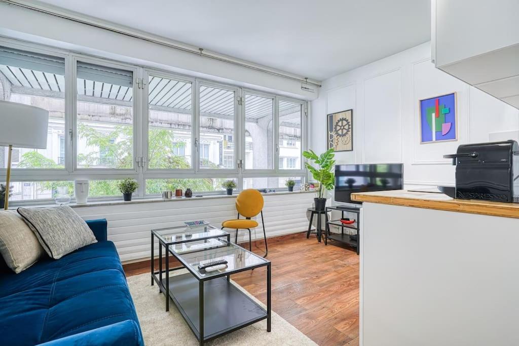 un salon avec un canapé bleu et une table dans l'établissement Apartment 4Pers - Montparnasse/St Germain, à Paris