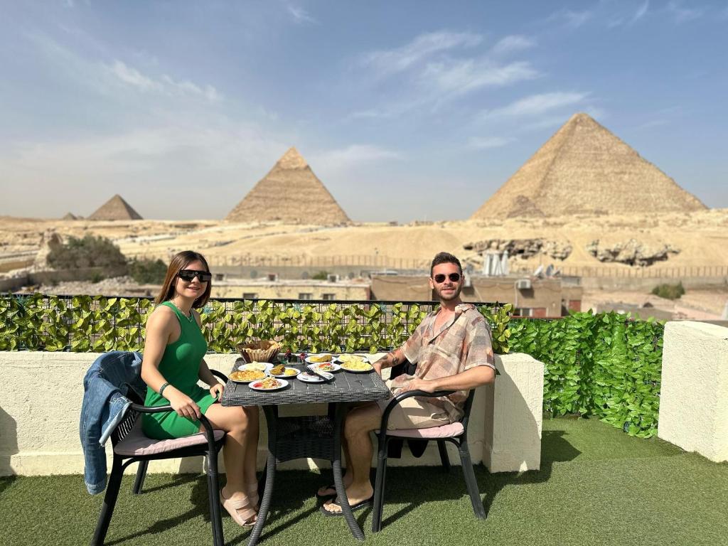 duas pessoas sentadas numa mesa em frente às pirâmides em Solima Pyramids View no Cairo