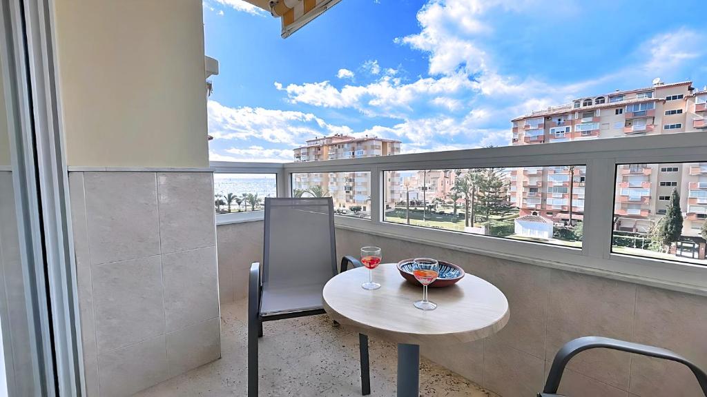einen Tisch mit einem Glas Wein auf dem Balkon mit Aussicht in der Unterkunft Zuhayra Beach Apartamento con Vista a 50m del Mar in Torrox Costa