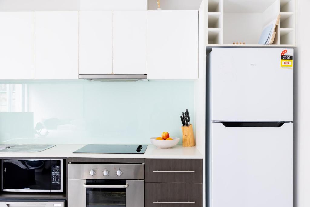 a kitchen with white cabinets and a refrigerator at The Apollo in Apollo Bay