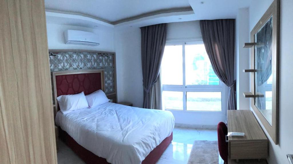 a bedroom with a bed and a large window at فنادير in Hurghada