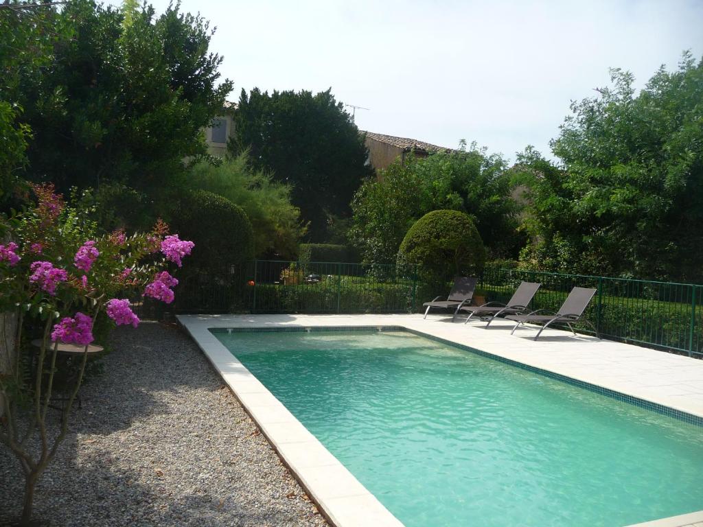 einen Pool mit Stühlen und Blumen im Hof in der Unterkunft Magnifique maison de famille - 3 mn à pied du centre in Uzès