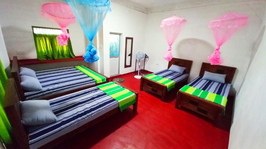 1 dormitorio con 2 camas y suelo rojo en Sewana Guest INN en Wellawaya