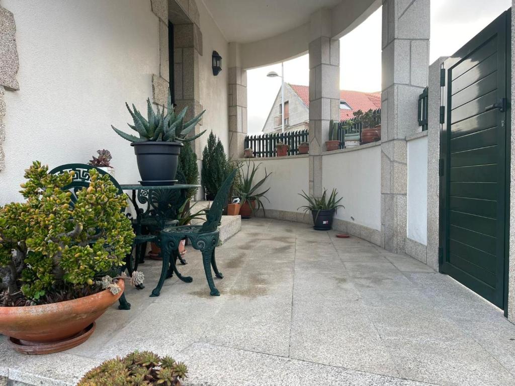 a patio with a table and chairs and potted plants at Casa Padriñan in Sanxenxo