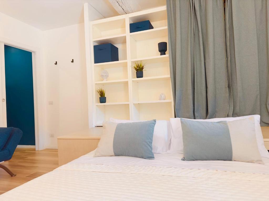a bedroom with a bed with white sheets and blue pillows at Modern Loft Rho Fiera Milano in Rho