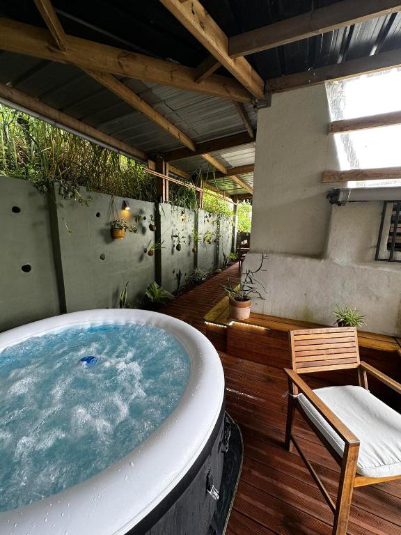 un bain à remous sur une terrasse avec une chaise et une table dans l'établissement Ti kaz cannelle, à Saint-Louis