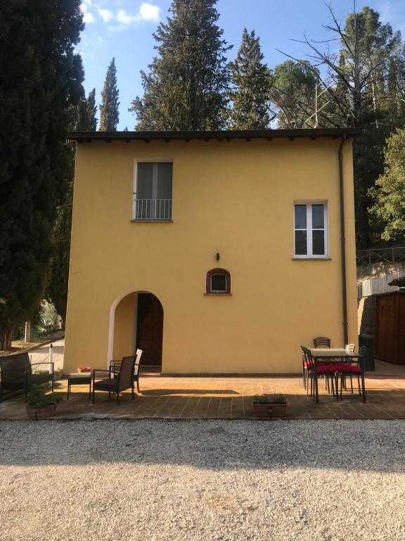 a yellow house with a table and chairs in front of it at La Casa delle Farfalle in Chiusi