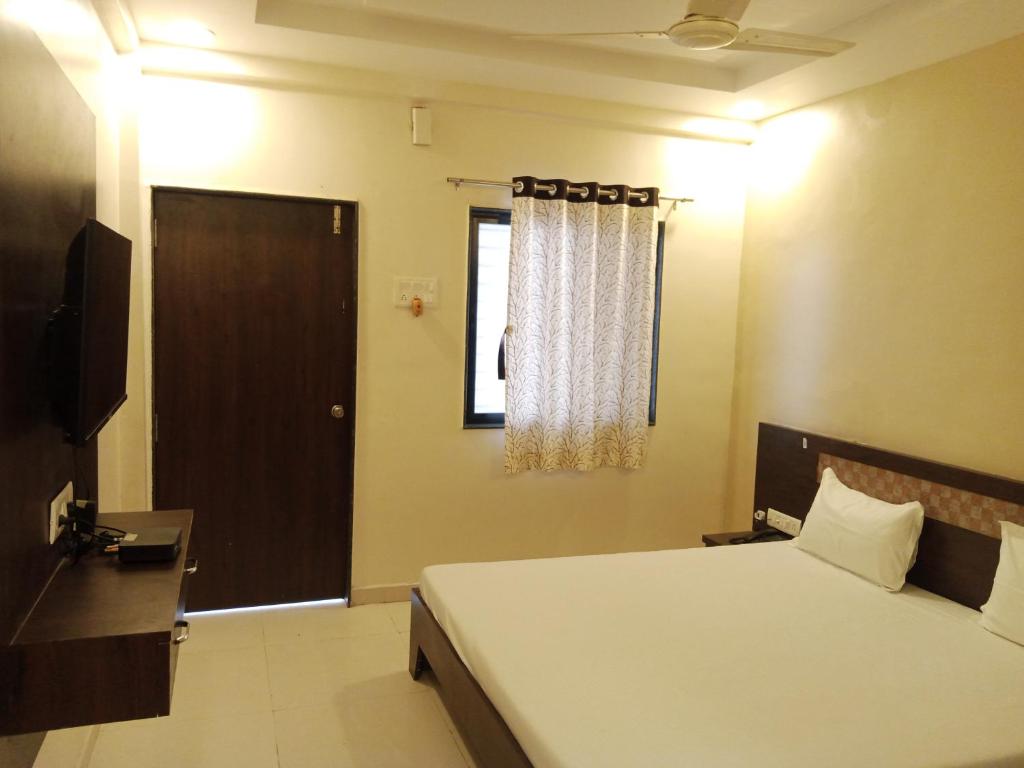 1 dormitorio con cama, puerta y ventana en Hotel Sharayu, en Sonai