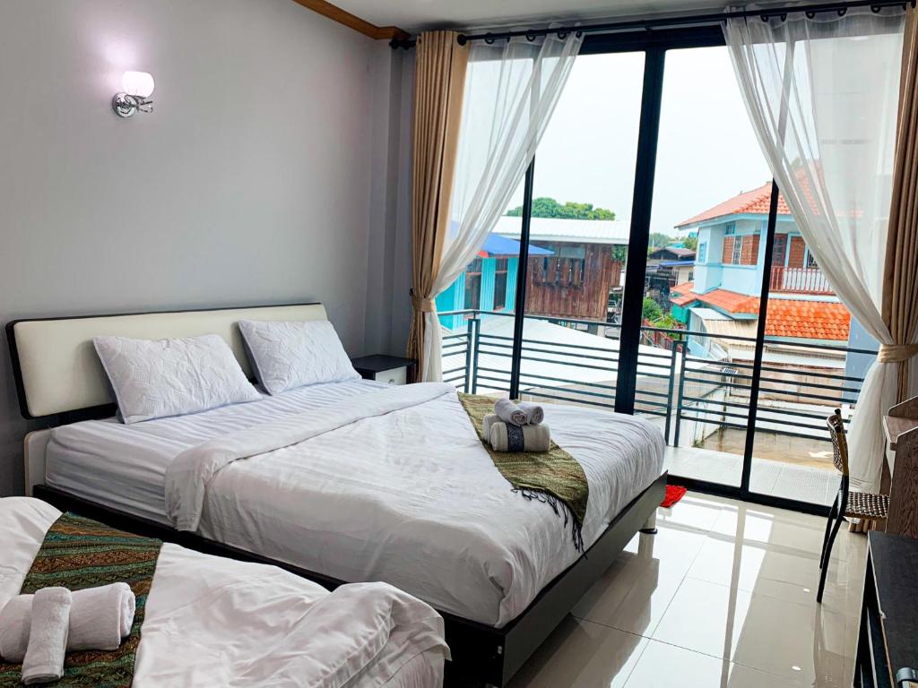een slaapkamer met een bed en een groot raam bij โรงแรม ทรี บริดจ์ โฮเทล in Nan