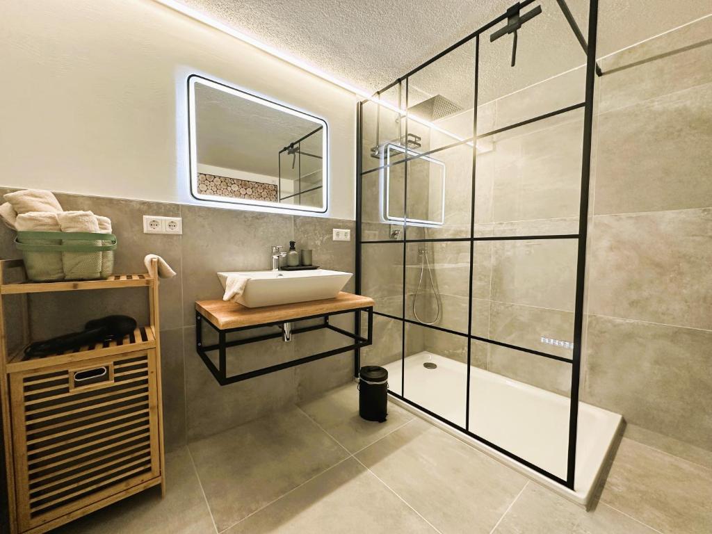 a bathroom with a sink and a glass shower at Rottweiler Ferienwohnung in Rottweil