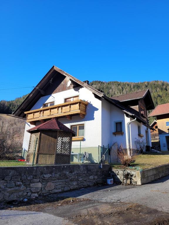 a white house with a wooden balcony on top at Ferienwohnung Biohof Untermar in Obervellach
