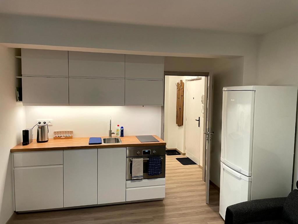 a kitchen with white cabinets and a refrigerator at Útulný byt pro odpočinek i práci in Kutná Hora