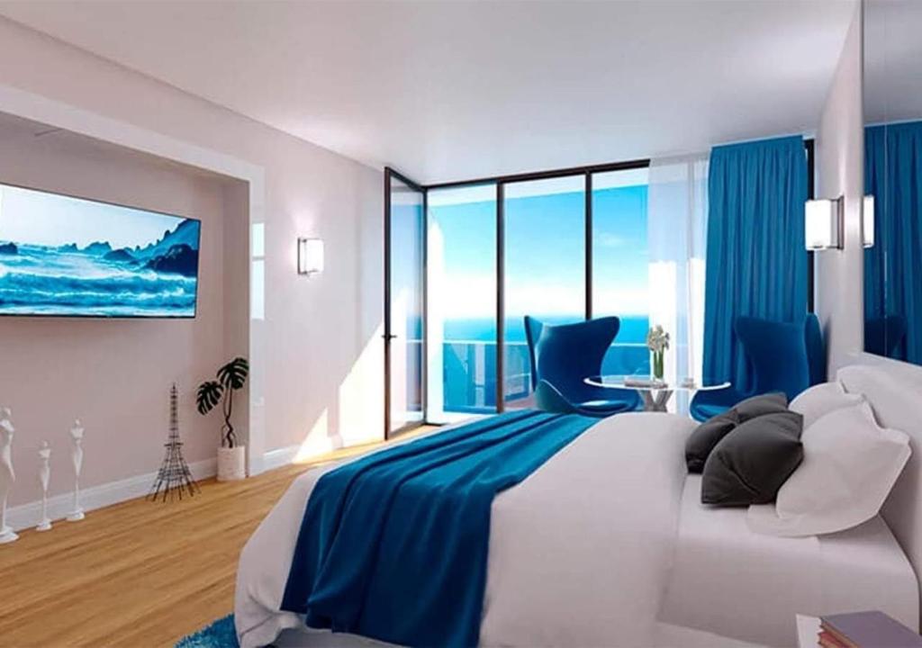 um quarto com uma cama grande e um cobertor azul em Orbi City sea view em Batumi