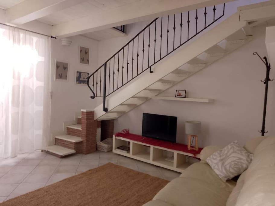un soggiorno con divano, TV e scale di Casa San Simon a Massa