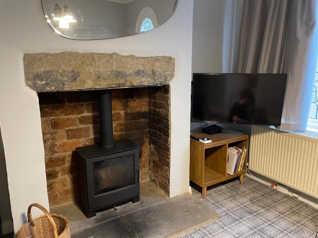 a living room with a fireplace and a television at Cosy 1BD Heritage Cottage in Saltaire, Shipley in Shipley