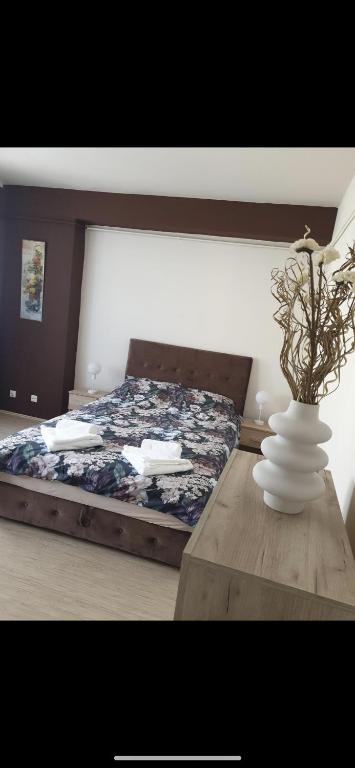 een slaapkamer met een bed met een vaas op een tafel bij Apartman Ivan in Vršac