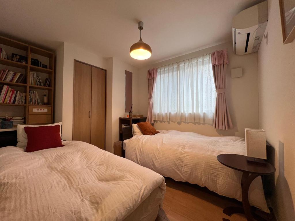a bedroom with two beds and a table and a window at Uhome Ikebukuro Villa 2 in Tokyo