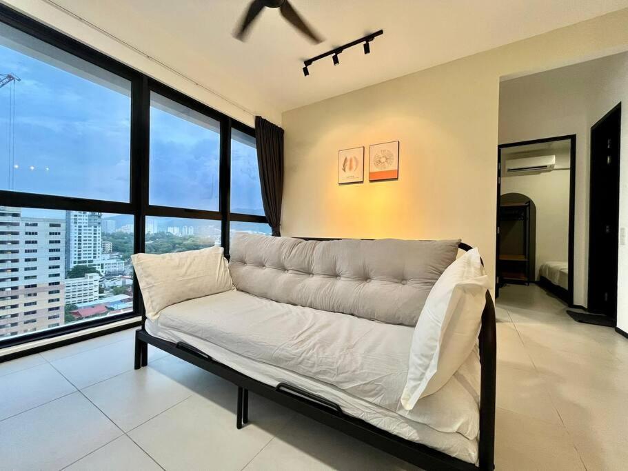 ein weißes Sofa in einem Zimmer mit großen Fenstern in der Unterkunft Urban Suite 3R2B 8Pax Georgetown in Jelutong