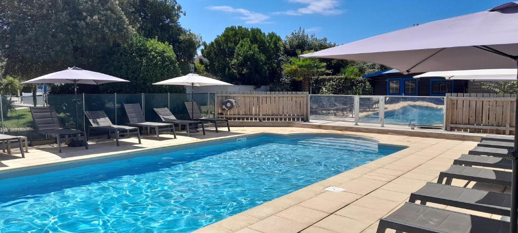 uma piscina com cadeiras e guarda-sóis ao lado em Logis Hôtel de la Plage em La Cotinière