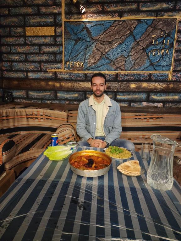 un hombre sentado en una mesa con una pizza en Petra Anas House, en Wadi Musa