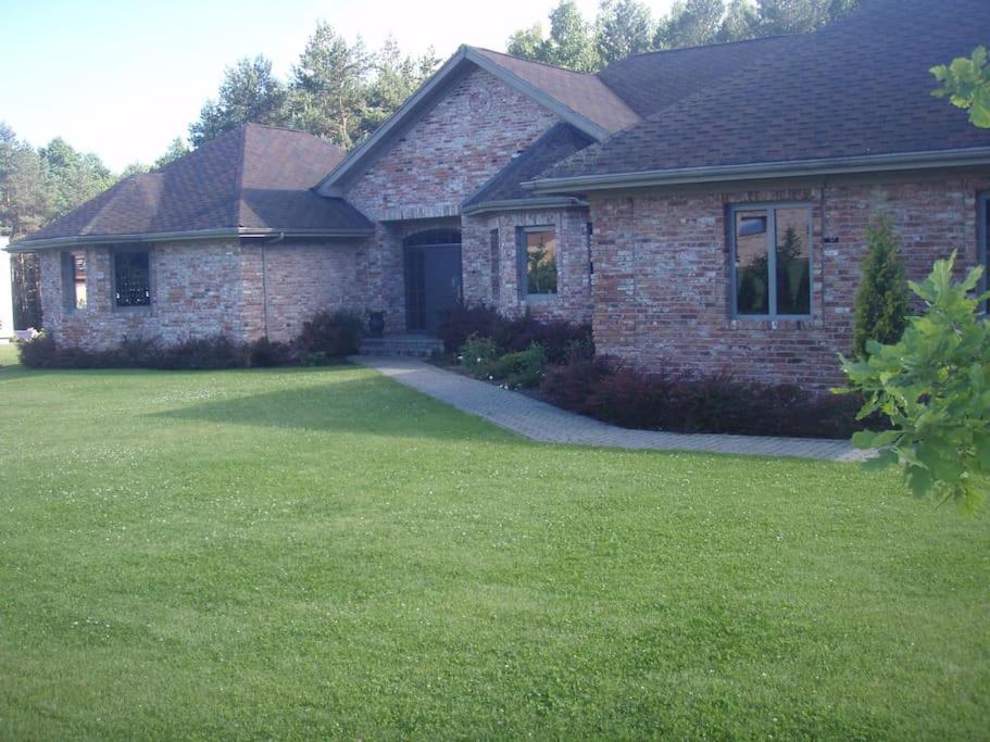 a brick house with a green lawn in front of it at Forest apartment in the loop of the river Neris in Verkšonys