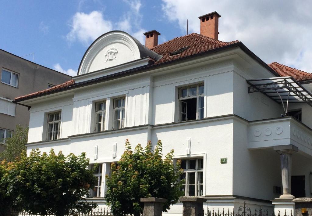 une maison blanche avec une horloge en haut dans l'établissement House Elza, à Ljubljana
