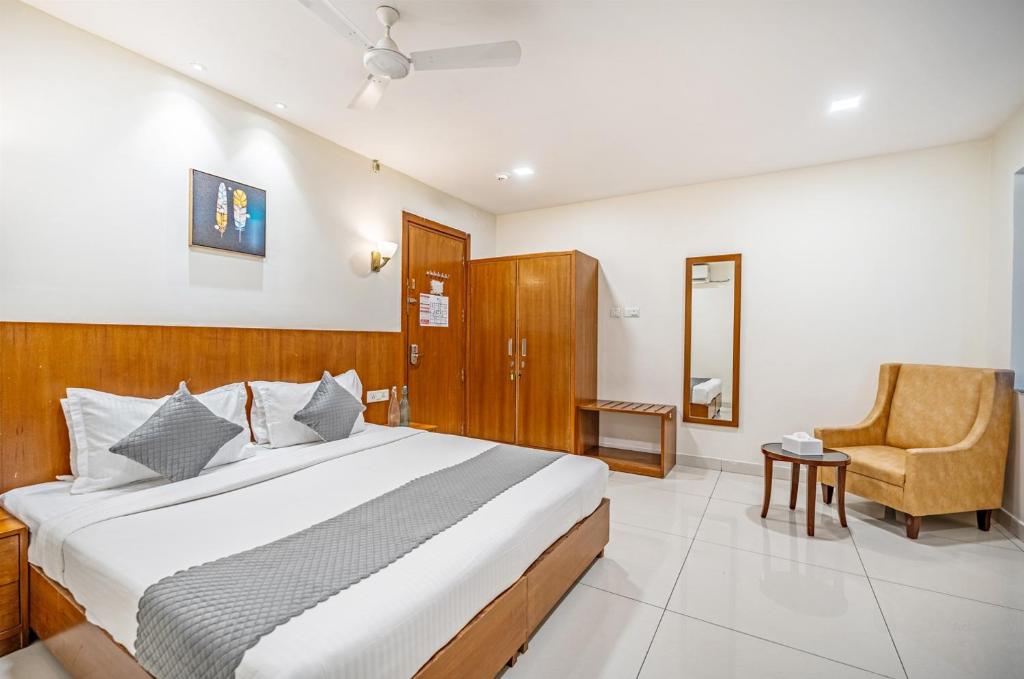 a bedroom with a large bed and a chair at WESTSIDE HOTEL HiTECH CITY in Hyderabad