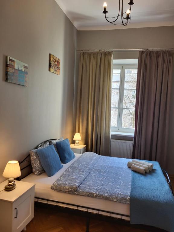 sypialnia z łóżkiem z niebieskimi poduszkami i oknem w obiekcie Novo Mundo w Warszawie