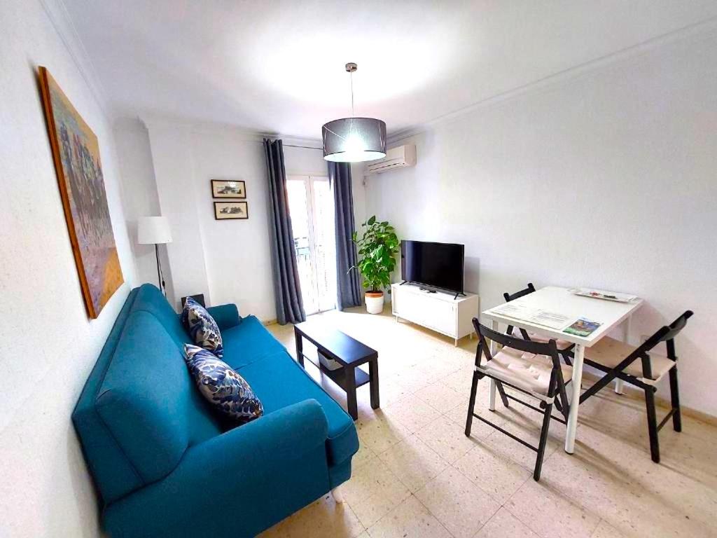 sala de estar con sofá azul y mesa en Sol Centro Apartment B, en Sevilla