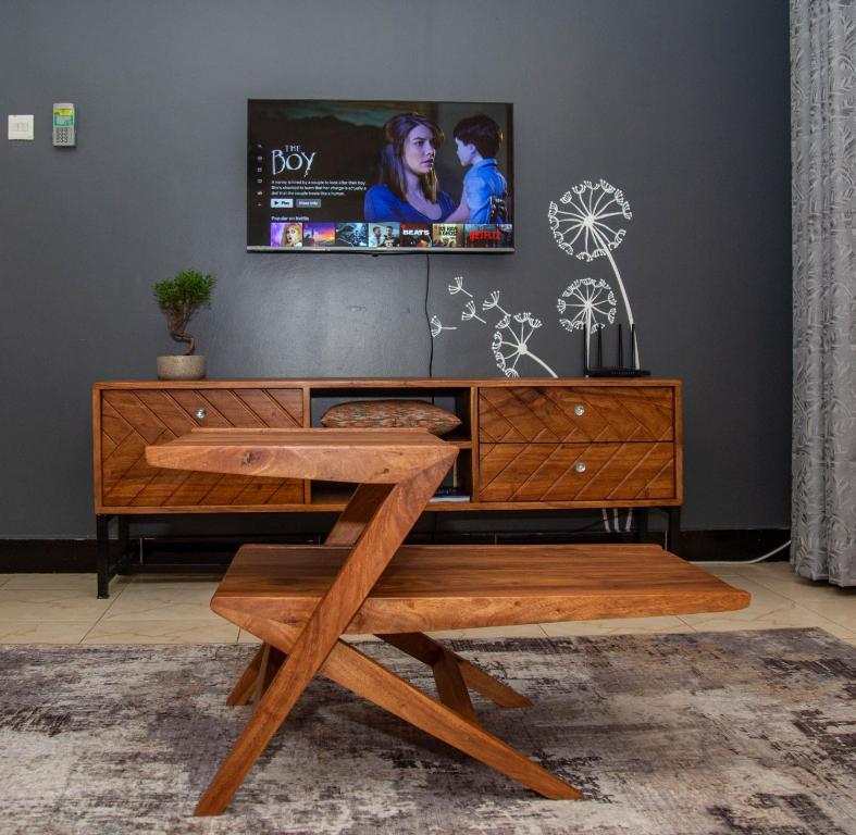 a living room with a tv and a wooden bench at Barryston Haven 1 in Kampala