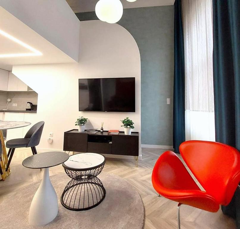 a living room with red chairs and a flat screen tv at Central Gallery Apartment in Debrecen