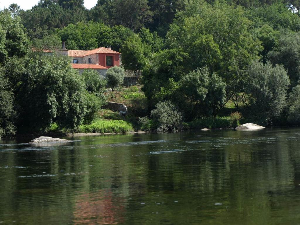 a house sitting on the bank of a river at Quinta Da Ribeira in Ponte de Lima